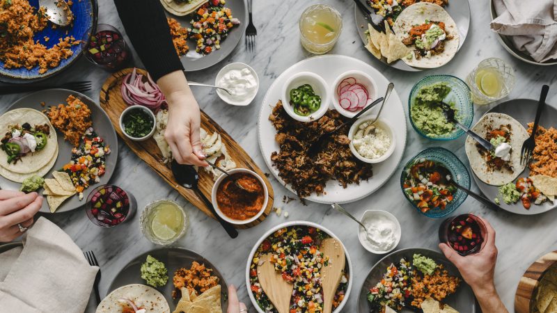 Cropped hands of friends having food at table during social gathering